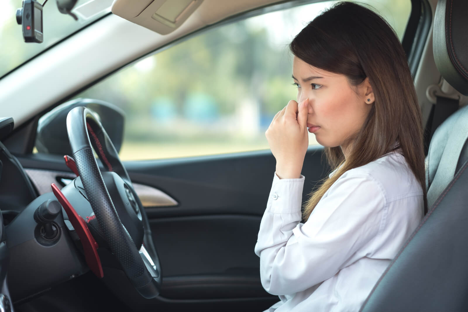 車の中で悪臭のため鼻を持つ女性